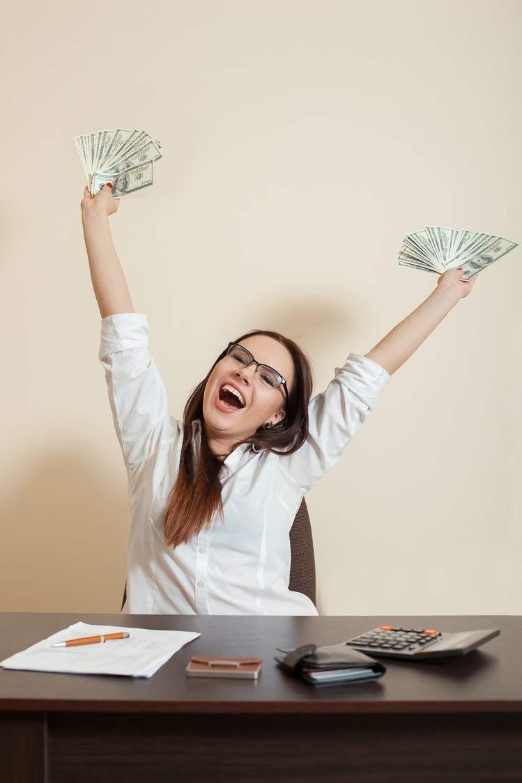 Smiling businesswoman throws up a pack of dollars